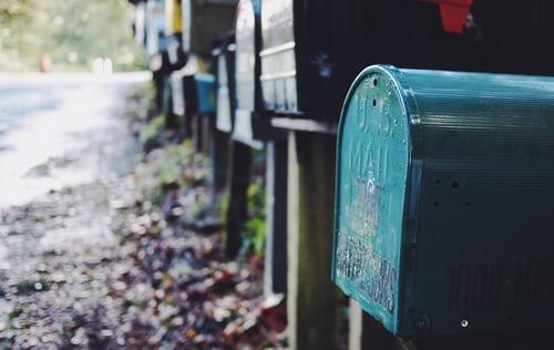 Une rangée de boîtes aux lettres alignées sur un chemin de campagne. 